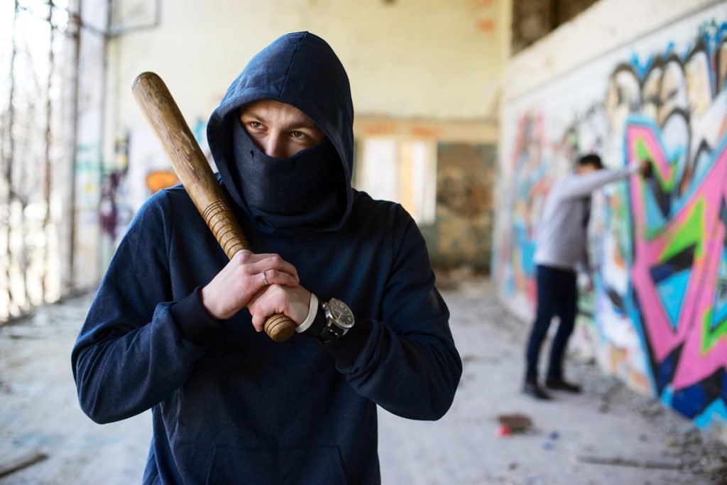 man wearing a hoodie holding a bat