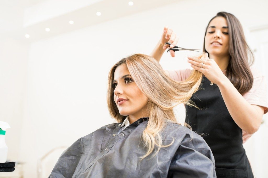 woman with long blond hair getting a trim at the salon