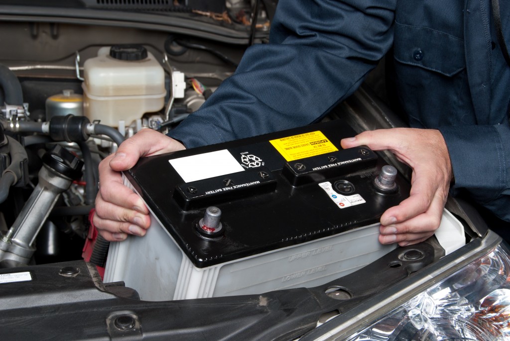 car mechanic replaces a battery