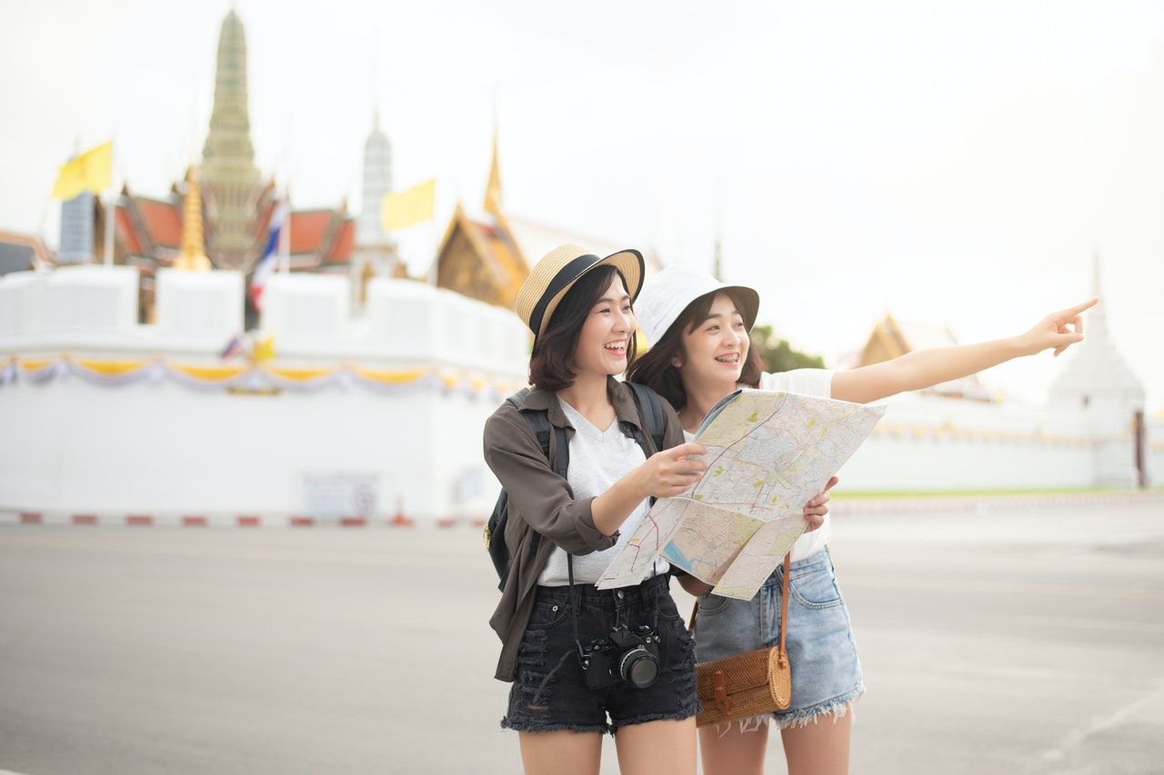 2 woman tourists holding map pointing